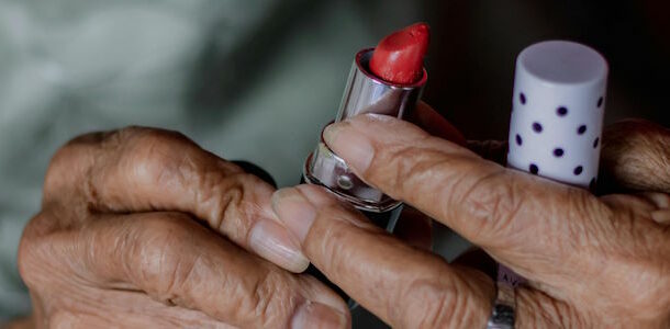 old hands holding red lipstick